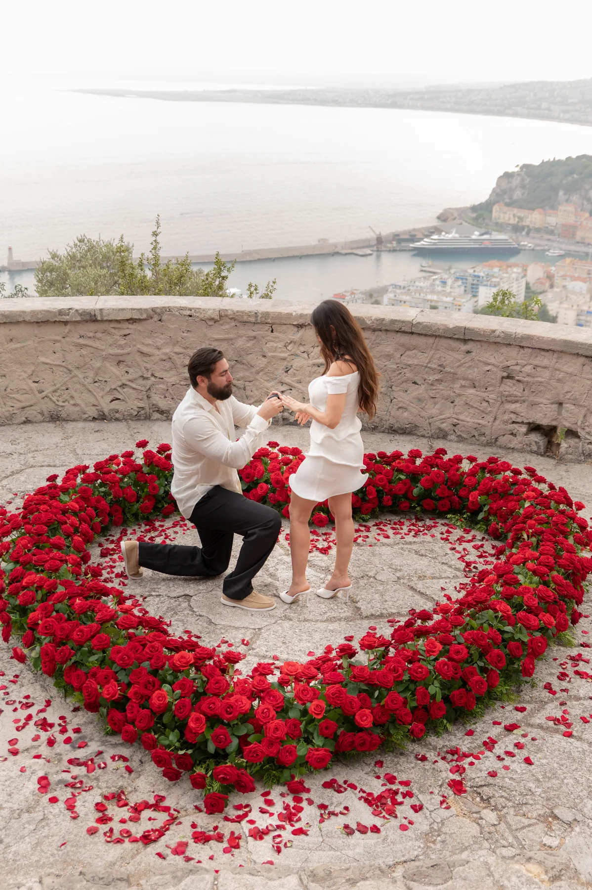 A man proposing inside a heart of red roses