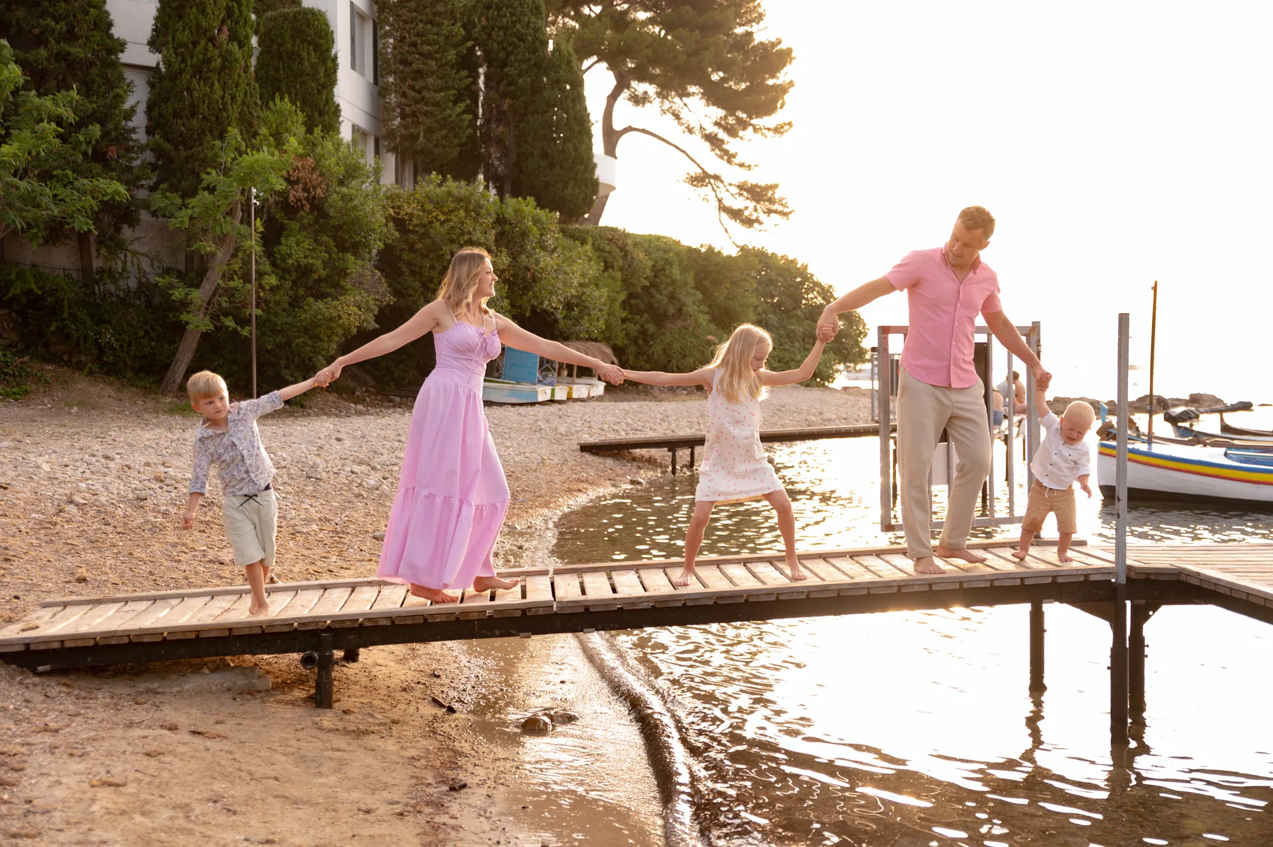 A family of five walking hand in hand along a wooden pier at sunset on the French Riviera